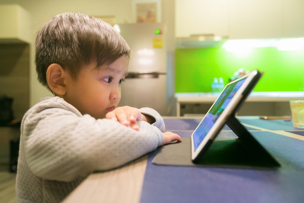 Photo boy looking at digital tablet on table at home