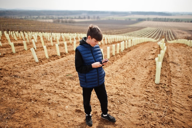 Boy looking at mobile phone against vineyard