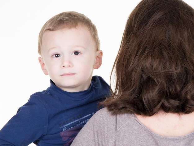 Boy looking over mother`s shoulder. The boy looks serious