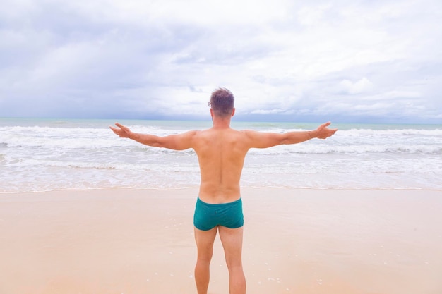 Boy looking at the sea from his back with arms outstretched