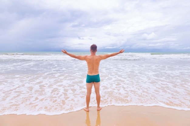 Ragazzo che guarda il mare dalla schiena con le braccia tese