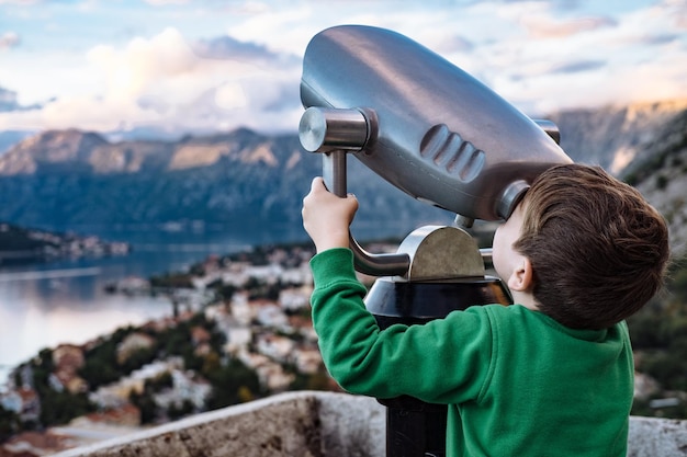 Boy looking through binocular at the city of Kotor Montenegro