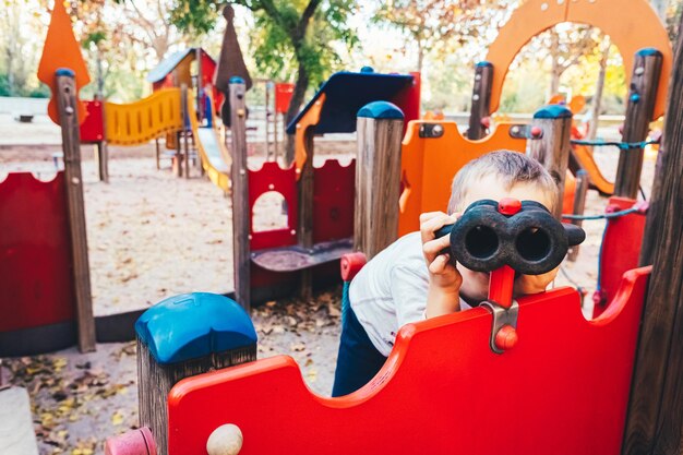 写真 遊び場で双眼鏡を見ている少年