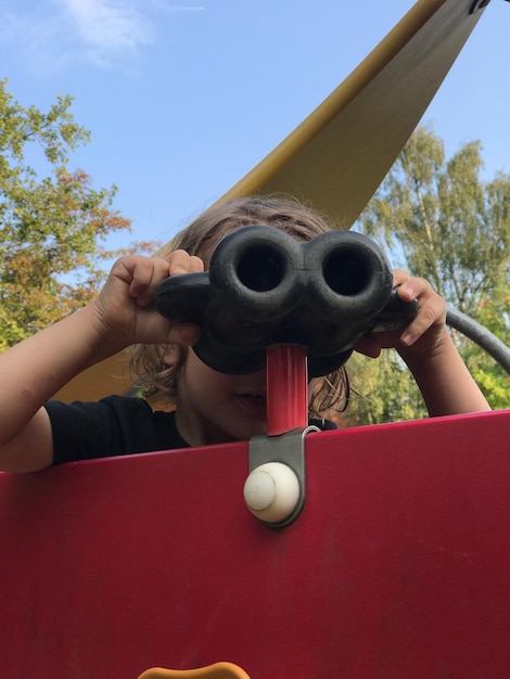 Boy looking through binoculars in park