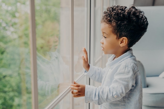 Photo boy looking through window at home