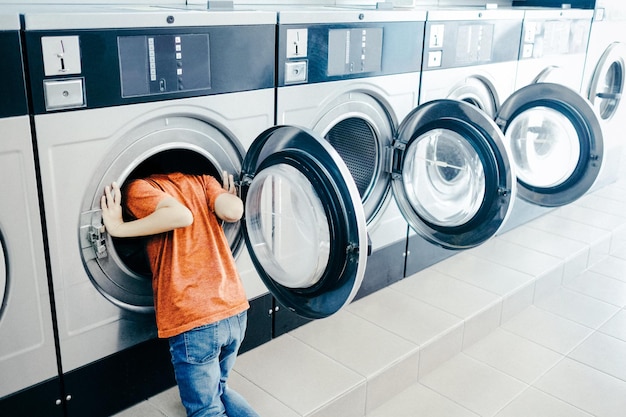 boy looking in washing machine at laundromat