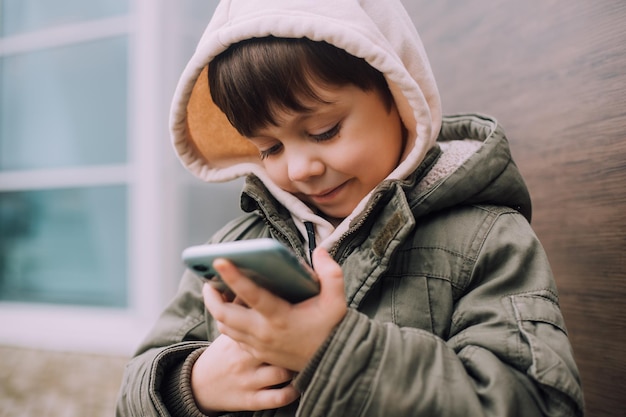ライフスタイルの街で携帯電話を見る少年 現代のテクノロジー 現代の子供たち 子供と電話