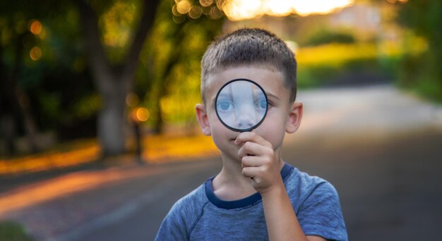 Photo boy looks into a magnifying glass selective focus nature