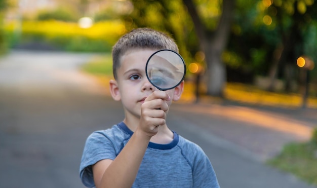 Photo boy looks into a magnifying glass selective focus nature