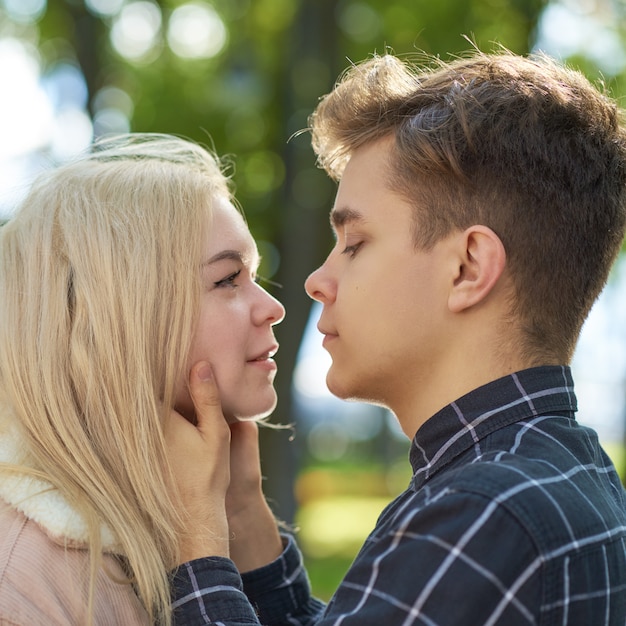 Il ragazzo guarda teneramente la ragazza, le mani giunte sul viso e vuole baciare