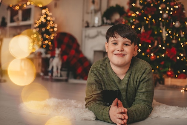 クリスマスの飾りに横たわっている少年