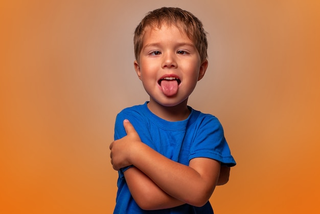 boy makes a face and shows his tongue on orange