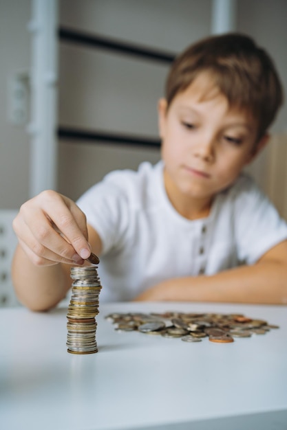 コインのピラミッドを作る少年。金融のABC。お金を数える少年。セレクティブフォーカスの画像