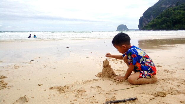 Photo boy making sandcastle at beach