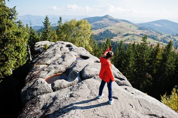 自撮りをする少年。山で美しい日にハイキングをしたり、岩の上で休んだり、山頂の素晴らしい景色を眺めたりする子供たち。子供とのアクティブな家族の休暇の余暇。屋外の楽しさと健康的な活動。