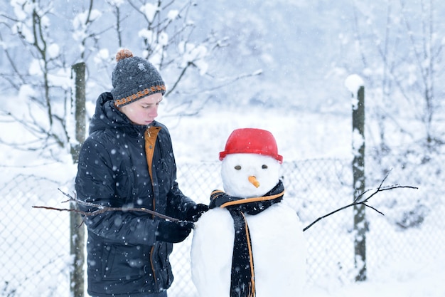 Мальчик делает снеговика, веселые зимние мероприятия