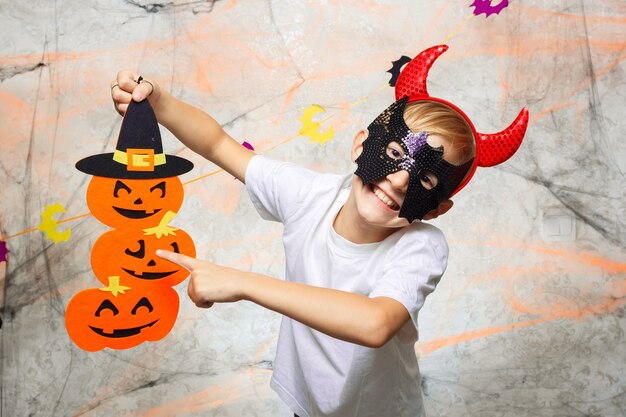 Foto ragazzo in una maschera che tiene una zucca per halloween