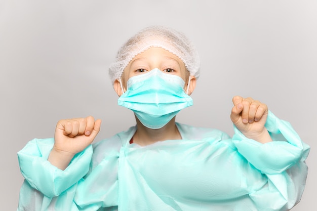 Photo a boy in a medical gown and mask in front of him hands clenched into a fist