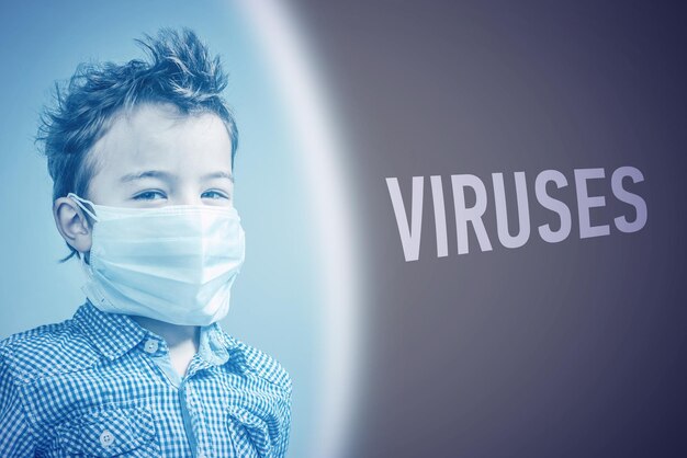 Boy in the medical mask next to inscription VIRUSES on brown background