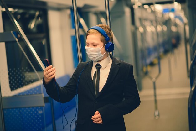 A boy in a medical mask is sad at the train window a child is traveling alone