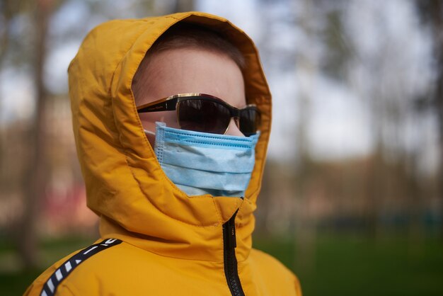 Foto ragazzo con maschera medica e occhiali da sole nel parco primaverile