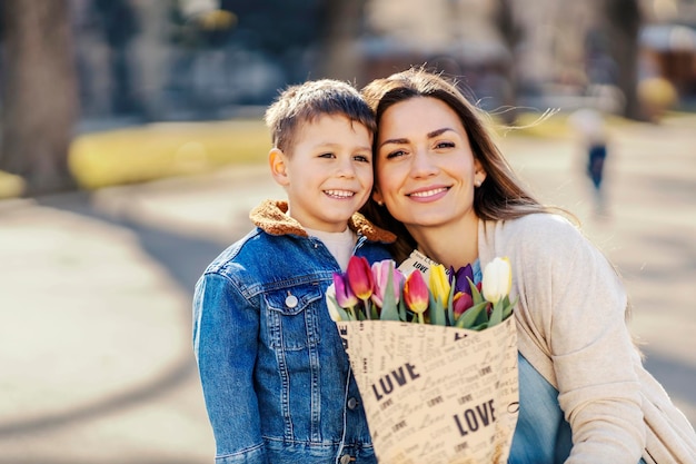 A boy and mother posing in park with flowers for mother39s day