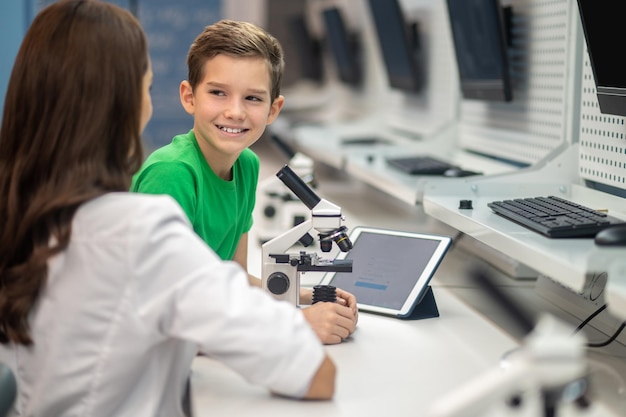 Boy near microscope looking at teacher