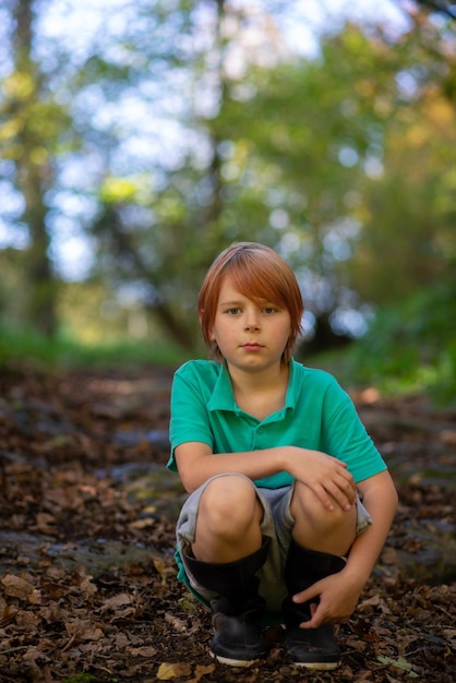 森の中の小道に一人で座っている 9 歳の男の子