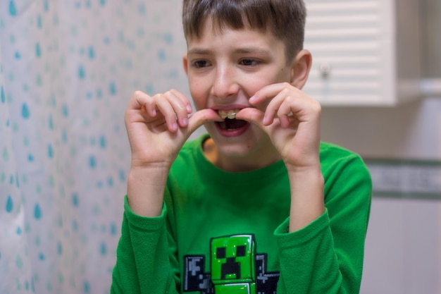 Мальчик, наблюдающий за зубными брекетами в зеркале