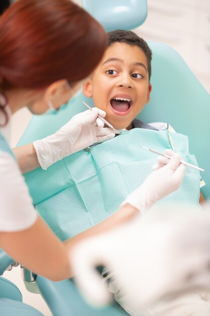 Boy opening mouth. Cheerful handsome boy opening mouth while having dental examination