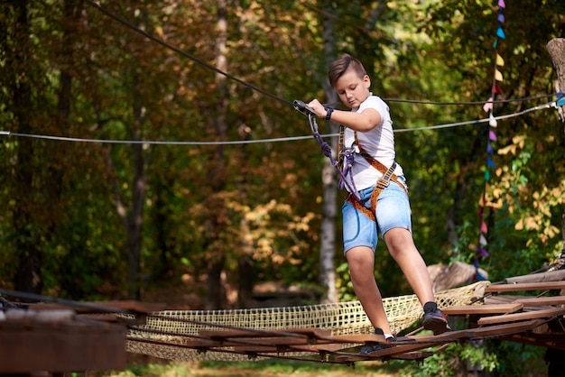 The boy overcomes the obstacle in the rope park.