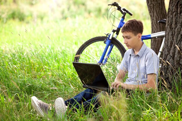 Мальчик в парке с ноутбуком