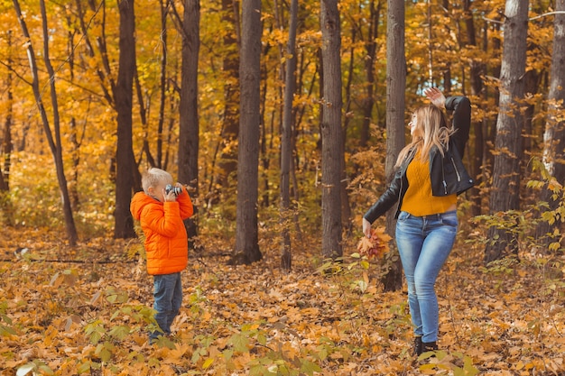 Boy photographer takes pictures of a mother in the park in autumn hobbies photo art and leisure