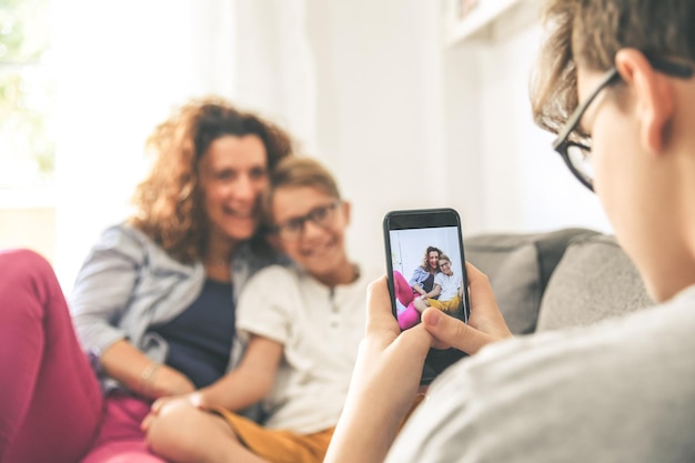 写真 家で携帯電話で母親と息子を撮影している少年