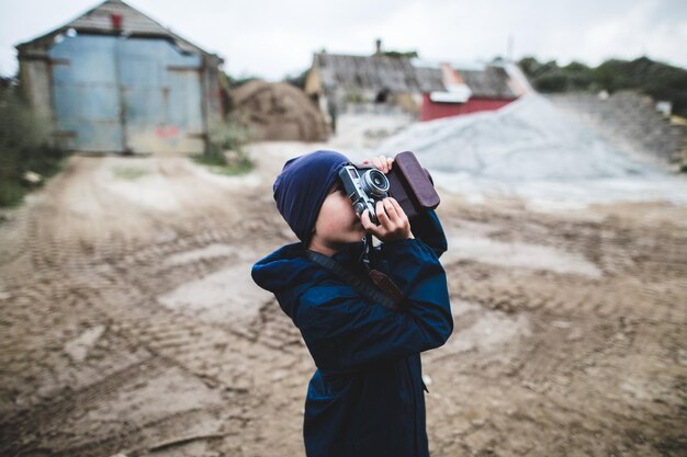 Фото Мальчик фотографирует, стоя на суше.