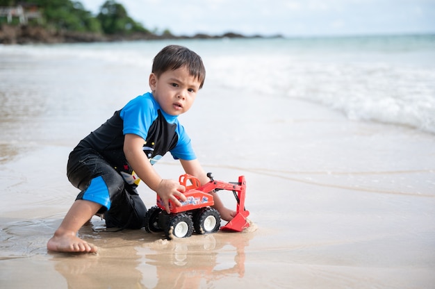 The boy play excavator toy on the beach