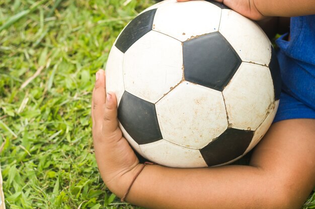 Boy play soccer in grass field.