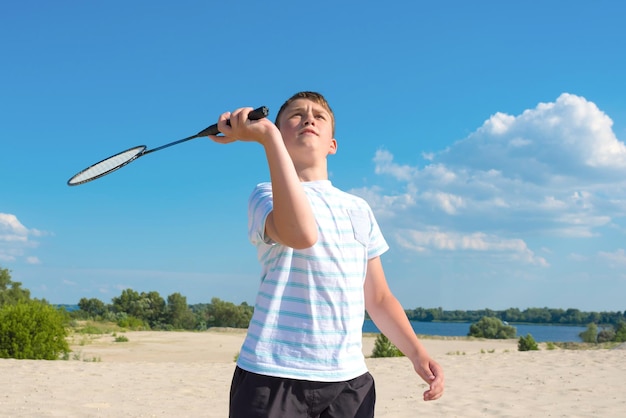 Boy playing badminton outdoors on the beach on a summer sunny day Healthy lifestyle