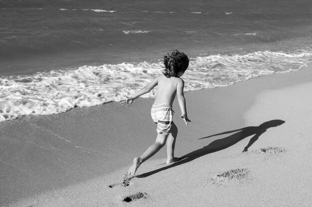 美しい海砂と青いランで自然の中で夏休みの子供たちのビーチで遊ぶ少年...