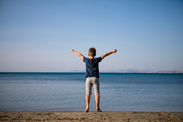 Boy playing on the beach on summer holidays Children in nature with beautiful sea sand and blue running in the sea water