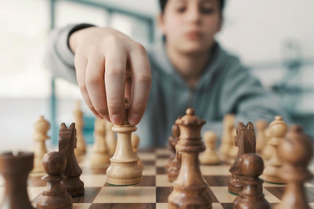 Мальчик играет в шахматы и передвигает фигуру