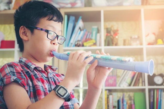 Boy playing the clarinet, trumpet at home, blowing a sweet flute, musicology background