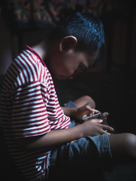 Photo boy playing game in mobile phone at home