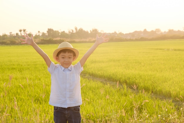 Photo boy playing in grass field at sunset