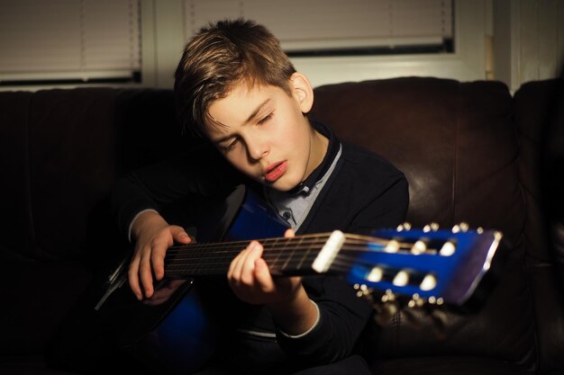 A boy playing a guitar on a couch