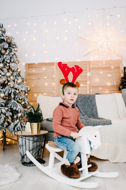 Boy playing near Christmas tree.  Merry Christmas. Christmas decorated interior. The concept of family holiday.