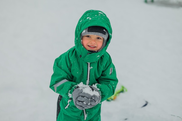 冬の屋外ゲームで屋外で遊ぶ少年小さな男の子が少年そりの後ろの雪の中で遊んでいます