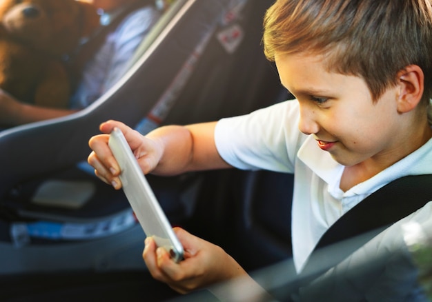 車の中のスマートフォンで遊んでいる少年