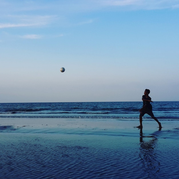 写真 ビーチでサッカーをしている少年