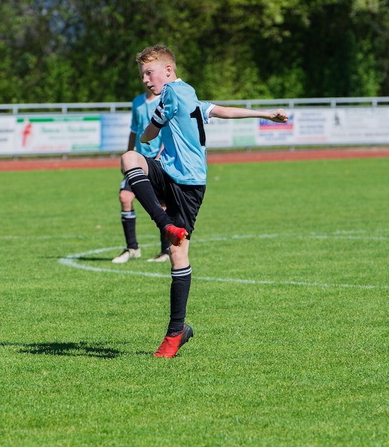 Foto ragazzo che gioca a calcio sul campo erboso